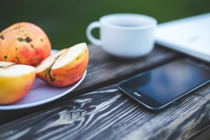 Telefon, äpplen, kaffe på bord.