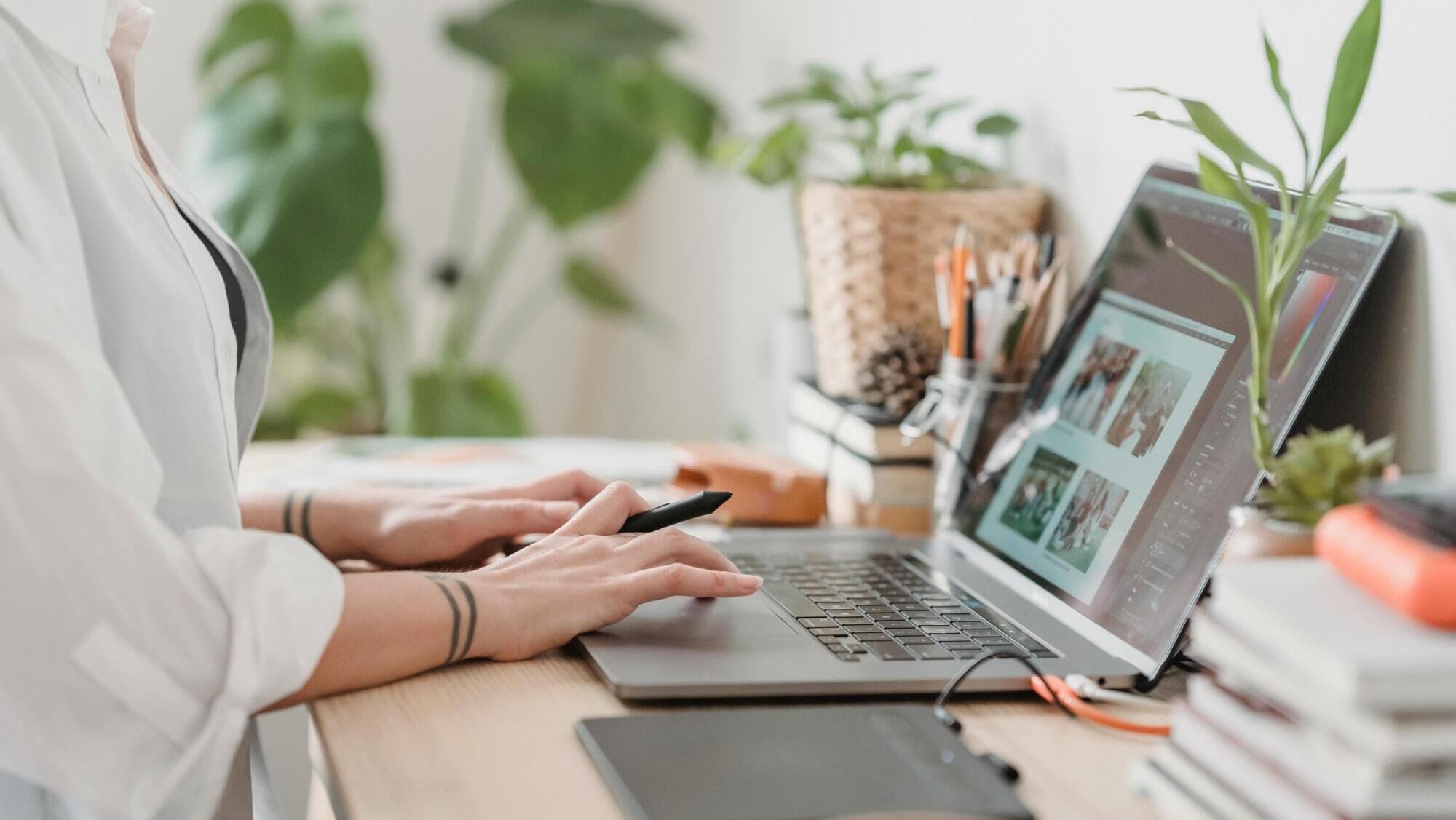 Kvinna som sitter och skriver på sin laptop, som symbol för bloggen